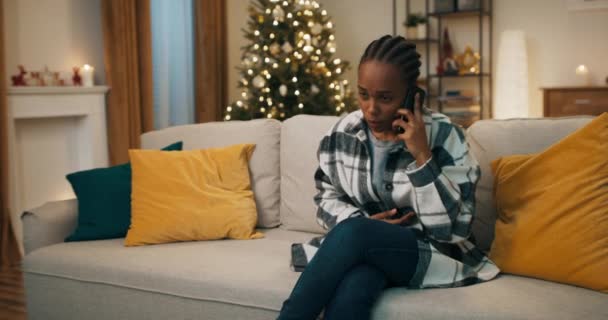 Młoda Kobieta Afrykańskim Wyglądzie Ubrana Szachownicę Siedzi Kanapie Rozmawia Przez — Wideo stockowe