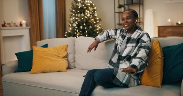Winter Evening Christmas Tree Flickers African Looking Student Sits Sofa — Stockvideo