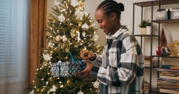 African Looking Student Stands Christmas Tree Unpacks Gift She Unties — Stockvideo