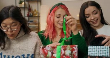 Noel partisi. Arkadaşlar kanepeye oturdu ve hediyeleri açma zamanı geldi. Kızlar kazaklarını, kalın şapkalarını aldılar ve aldıkları şeyle çok mutlular. Çocukların ellerinde hediyeler var ve iletişim kuruyorlar..