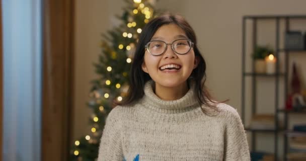 Uśmiechnięta Dziewczyna Okularach Azjatyckiego Wyglądu Podziwia Świąteczne Dekoracje Salonie Jest — Wideo stockowe