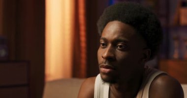 Siyah saçlı, Afro saçlı, Afro-Amerikan kökenli ciddi yakışıklı bir adamın yüz portresi. Arka plandaki kameraya bakıyor..