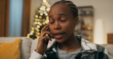 Afrika görünümlü çekici bir kız oturma odasında kanepede oturuyor. Kız kardeşiyle telefonda konuşuyor, duygusal olarak günden ve yeni alımdan bahsediyor. Odada bir Noel ağacı sallanıyor..