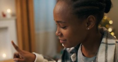 Ekose gömlek giyen Afrikalı bir kadın görüntülü konuşma yapar ve iş arkadaşıyla iletişim kurar. Katılmıyor ve başını sallıyor. Kadın tartışıyor. Arka planda Noel süslemeleri parıldıyor.