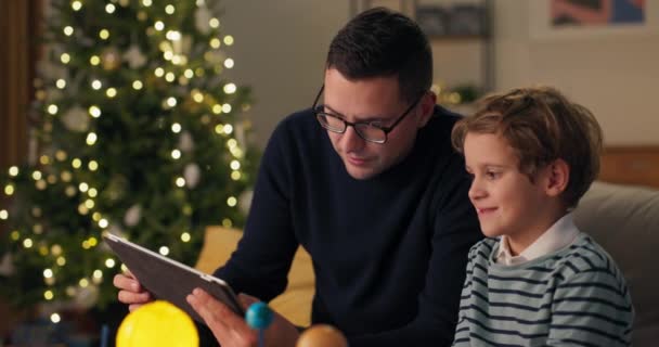 Babam Çocuklara Noel Akşamında Oyuncakların Incelenmesini Öğretir Tablet Güneş Sisteminin — Stok video