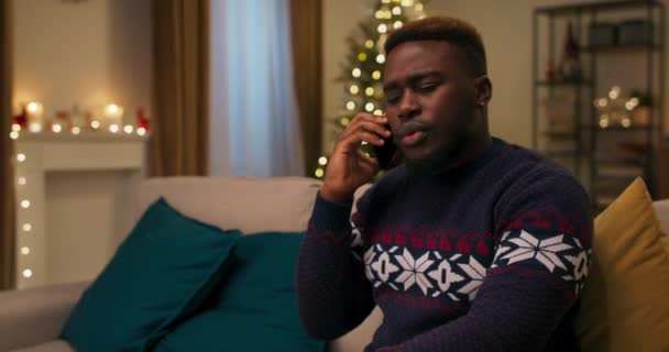 Ung Man Med Afrikanskt Utseende Sitter Soffan Och Pratar Telefon — Stockvideo