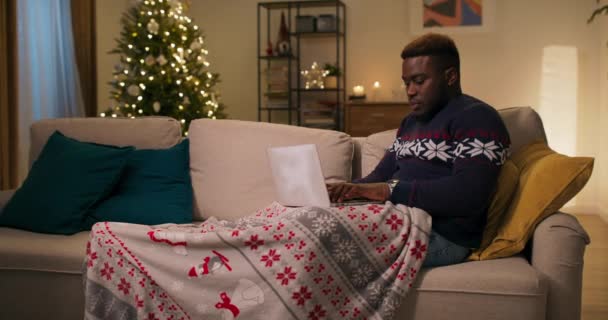 Ein Junger Mann Afrikanischen Aussehens Sitzt Auf Einem Sofa Und — Stockvideo