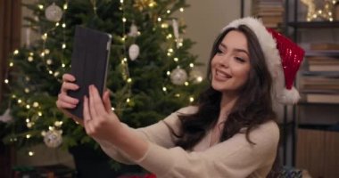Güzel bir öğrenci Noel ağacının yanında oturur ve erkek arkadaşıyla tablette görüntülü konuşma yapar. Kız tatilde onu tebrik eder, iletişim kurar, gülümser ve onun için hazırladığı hediyeyi gösterir..