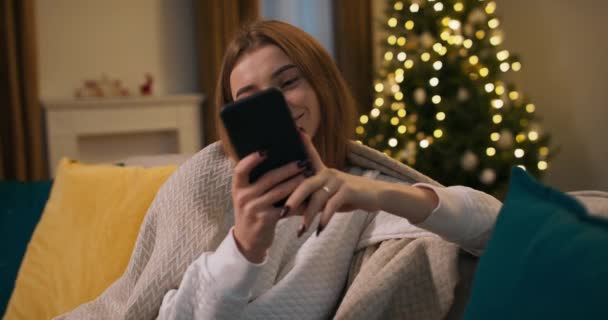 一个悲伤的女孩在等着家人的圣诞祝福电话 她和她的朋友说话 她笑着 他们互相祝对方圣诞快乐 — 图库视频影像
