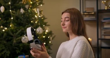 Işıklarla aydınlatılmış bir Noel ağacının yanında oturan bir kız, akşam yemeği hazırlıkları, bir kadın sevdiği birine hediye olarak bir kutuda sakladığı kulaklıklara bakar..