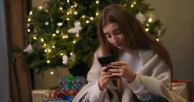 Üzgün kız, Noel ağacının yanında, battaniyeye sarılmış halde oturuyor. Noel 'i evinden uzakta tek başına geçiriyor. Hiç telefon almamış..