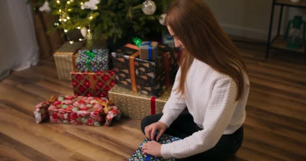 Woman Packing Christmas Gift Boxes Floor Stacked Christmas Tree Waiting — Stock Video