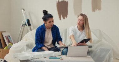 Genç bir Asyalı güzel kadın, mimar olan güzel sarışın bir kadın tarafından onun için hazırlanmış yeni bir daire tasarımı projesinden memnun. Kadınlar birbirleriyle çok iyi anlaşıyor, gülümsüyorlar..