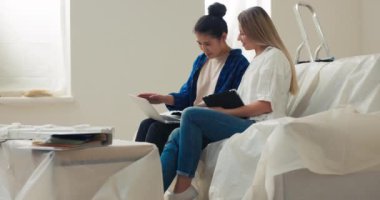Asyalı güzel bir kadın dairesinde tadilata başladı. Tasarımcıyla birlikte kanepede oturup bu sezon hangi duvar renginin moda olduğunu tartışıyorlar..