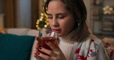 Akşamları elinde bir kupa sıcak çay tutan kadın elleri. Genç bir kız, ışıklandırılmış bir Noel ağacının atmosferindeki battaniyenin altında en sevdiği içecekle rahatlıyor. Kış havası.