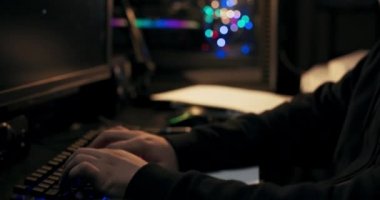 Klavyede daktilo eden çocukların yakın çekimi. Hacker 'ın başarıyla tamamladığı yeni bir görevi var. Adam gülümsedi, ellerini ovuşturdu, bir fincan kahve aldı ve bir yudum aldı. Adamın sakalı ve şapkası var..