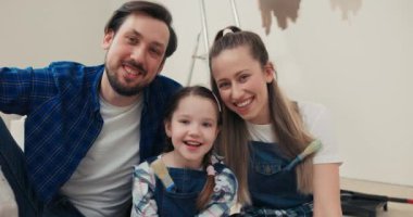 Yeni dairede mutlu bir aile. Yerde oturan yakışıklı, orta yaşlı bir adam güzel bir eş ve çok tatlı bir kız çocuğu. Kot pantolon ve kareli gömlek giyen bir adam kızına sarılıyor..