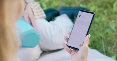Kızın akıllı telefonuyla uygulamayı kullanarak hoparlörü eşleştirdiği telefonun yakın çekimi. Bluetooth 'u bağlamak ve açık havada müzik çalmak.