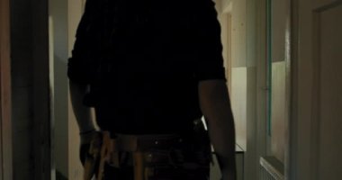 Elektrikçi bir alet çantasıyla eve girer, lavaboyu tamir eder, daireyi yeniler. Gömlek, iş pantolonu ve şapka giymiş bir adam..