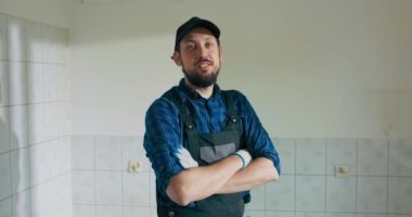 İnşaat alanında çalışmak için tutulmuş gülümseyen bir adamın portresi. Adam yıkım aşamasındaki bir odada dinleniyor. Tadilata ara verdik..