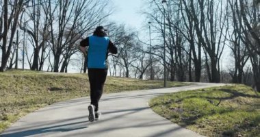 Güneşli bir kış sabahı. Adam parkta koşar ve etrafa bakar. Siyah ve mavi spor kıyafetleri giyiyordu ve başında şapka ve kulaklık vardı. Müzik dinler ve yola doğru koşar..