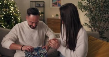 Noel arifesi. Çekici bir esmer kocasına hediye verir. Çift oturma odasındaki kanepede oturuyor. Erkek hediyeyi açar, mutlu bir şekilde gülümser ve karısına sarılır. İkisi de mutlu..