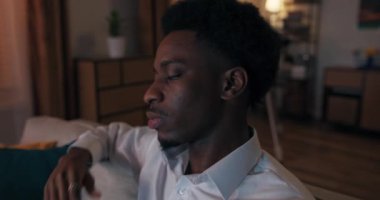 Zor günlerden sonra, Afrikalı görünümlü genç adam kanepede oturuyor ve televizyon izliyor. Adam yorgun, elleriyle gözlerini ovuşturuyor ve başını kanepenin arkasına yaslıyor. Beyaz gömlek giyiyor..