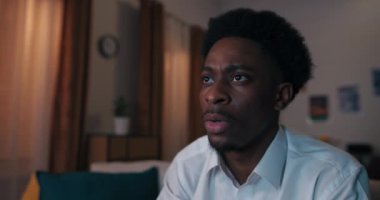 Konsol oyunu oynayan Afrikalı çekici görünümlü adamın yakın çekimi. Öğrenci beyaz gömlek giyiyor. Çocuk duygusal olarak joystick 'e basıyor ve bir sonraki seviyeyi geçiyor..