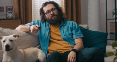 Oduncu tipli adam oturma odasındaki kanepede oturur uzaktan kumandalı hoparlörlerden müzik açar ve sosyal medya içeriğini izlerdi. Üniversite öğrencisi telefondaki bankacılık uygulamasında hesap bakiyesini kontrol ediyor.