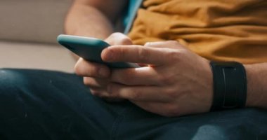 Genç adam telefon kullanıyor, elleri ekranda kayıyor, mesajlar yazıyor, sosyal medyada geziniyor, köpek adamın kucağına koşuyor..