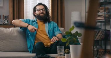 Gözlüklü sakallı bir adam işten sonra dinlenir. Kanepede yorulur ve televizyonu açar. Müzik kulesi, sevgili köpeğini kanepede zıplatır..