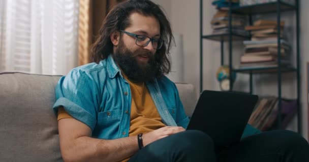 Mężczyzna Siedzi Domu Kanapie Laptopem Kolanach Używa Komputera Zdalnych Spraw — Wideo stockowe