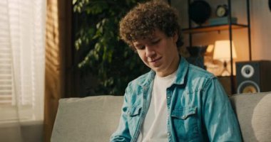 Kot gömlekli, genç, gülümseyen bir adam oturma odasında bir kanepede oturuyor. Öğrenci bir sözlük ve akıllı telefon tutuyor, mesajlar gönderiyor..