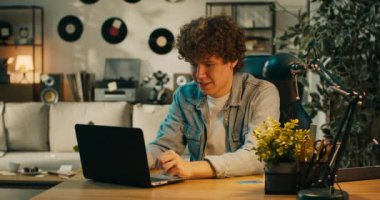 Siyah saçlı genç bir çocuk dizüstü bilgisayarına bakıyor, yanında bir kredi kartı var. Adam pek çok denemeden sonra banka hesabına girmeyi başardığı için memnun..