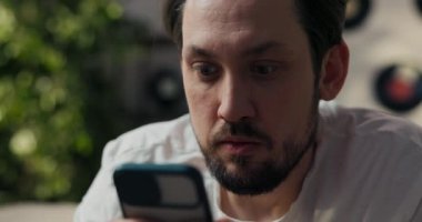 Şok olmuş adam telefona bakıyor, şaşırtıcı bilgiler, kötü haberler, tatsız sürprizler, adam ekranda büyük gözler yapıyor..
