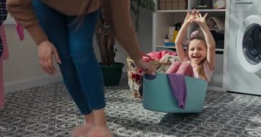 Büyük kız kardeş küçük kız kardeşle oynuyor. Kızı lavaboya koyuyor ve banyoda yuvarlanıyor. Altı yaşındaki bir kız yüksek sesle gülüyor ve el sallıyor. Yıkanmış giysiler arkada asılı..