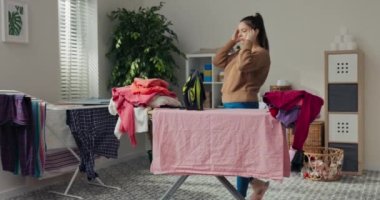 Odanın ortasında, üzerinde buruşmuş giysiler olan ütü masası var. Yorgun kadın odaya girer, başını tutar, nefes verir ve ütülemeye başlar. Daha yapılacak çok iş var..