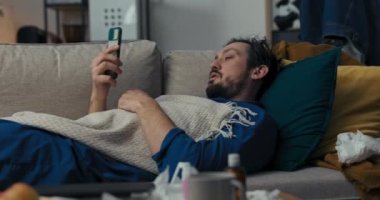 Siyah saçlı ve sakallı genç adam kanepede uzanıyor ve uyuyor. Kız arkadaşı aradı ve yemeğe davet etti. Mavi pijamalı adam hastalandı, o da reddetti. Üstünü battaniyeyle örttü ve uykuya daldı.