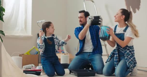 Lycklig Familj Flyttade Ett Nytt Hus Sitter Golvet Håller Målarhinkar — Stockvideo