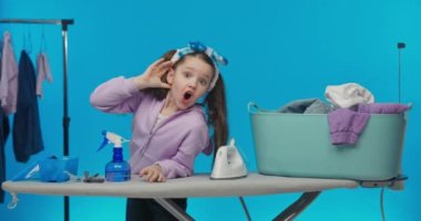 Kıyafetleri ütülüyorum. Mutlu gülümseyen kız elini kulağına koyar ve dinler..