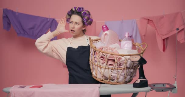 Женщина Прижимает Руку Уху Слушает Держа Отмытую Одежду Плетеной Корзины — стоковое видео