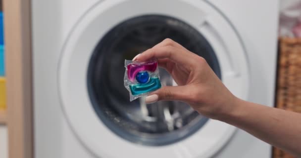 Närbild Händer Som Håller Mjuk Tvättkapsel Mot Bakgrund Tvättmaskin — Stockvideo