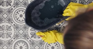 Yerleri mikrofiber bez ve paspas kovasıyla temizleyen bir kadının yakın çekimi..