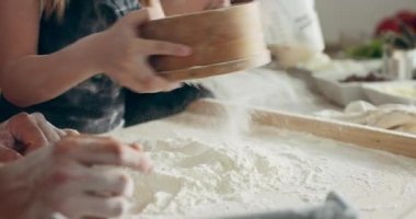 Yakın çekim çocuklar, genç anne ve babaya un süzmede yardım ediyorlar ev yapımı hamuru kurabiyeler, makarna, pizza gnocchi için hazırlıyorlar. Modern mutfakta mutlu aile kavramı.