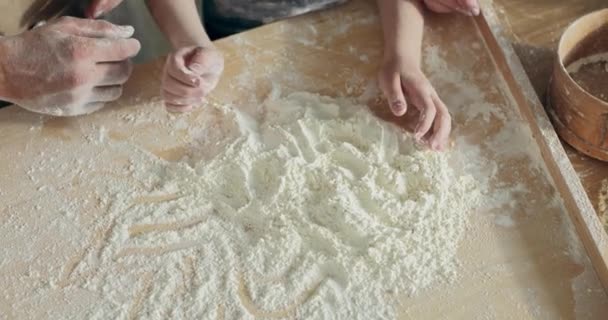 ピザパスタ用の自家製生地を準備しながら キッチンで木製の表面テーブルの上に小麦粉で遊んで子供の手 現代のキッチンで幸せな家族のコンセプト — ストック動画