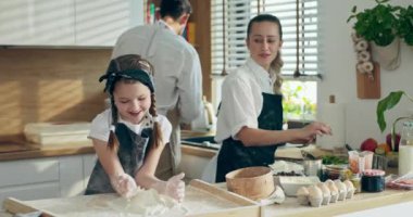 Karısı ve anaokulu kızıyla ev yapımı pizza pişiren önlüklü mutlu bir baba. Küçük sevimli kıza kuşkonmaz gösteren bir adam. Mutlu çocuk hamur yoğuruyor, ailesine pizza pişirmede yardım ediyor. .