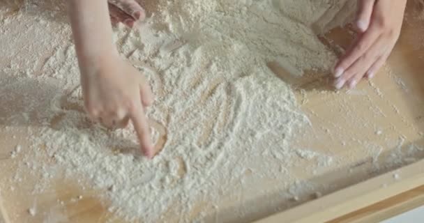 子供たちは木製の表面に小麦粉で心臓の形を描く手 ベーキングプロセスの概念 — ストック動画