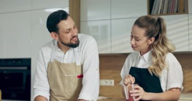 Sevgili eş ve koca modern mutfakta konuşarak domates sosunu ölçülü kapta karıştırarak ev yapımı pizzaya hamur hazırlıyor. Mutlu aile eğleniyor. Yemek pişirme süreci.