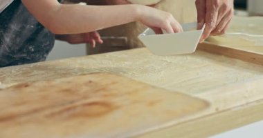 Seçici odak noktası yakın çekim yapan adamlar ve çocukların elleri kaseden un alıp tahta yüzeye pizza hamuru atıyor. Elleri yoğurarak ahşap yüzeyde pizzaya ev hamuru hazırlıyor..