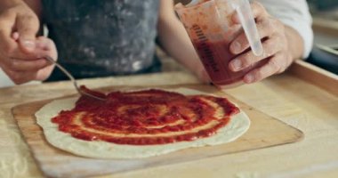 Yakın çekim babalar küçük sevimli çocukların ellerini tutarak ahşap yüzeyde hazırlanmış ev yapımı ev yapımı pizzaya domates sosu döküyorlar. Hafta sonları aile toplantısı.